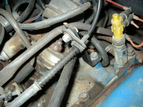 1985 Ford Bronco - Close-up view of engine components, including hoses, wires, and a yellow sensor.