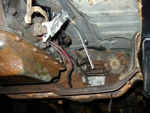 Close-up of vehicle transmission shifter linkage with rusty components and wiring