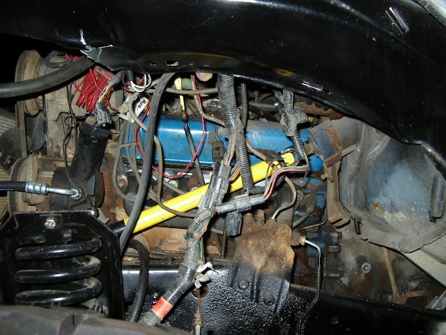 Engine bay closeup with blue valve cover, yellow part and wiring harness connectors