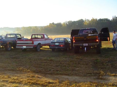 1979 Ford Bronco - A collection of trucks and a car are parked in a field, possibly at an event.