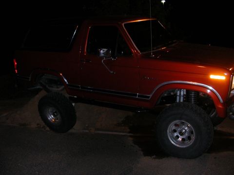 1984 Ford Bronco - This lifted Ford Bronco is shown from the front-three-quarter view, with its tires on a dirt pile.