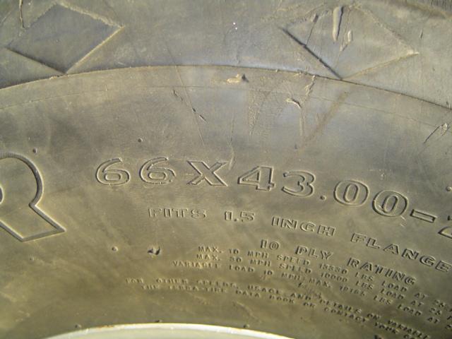 Close-up of a large tire with text indicating size 66x43.00-25 and 10 ply rating