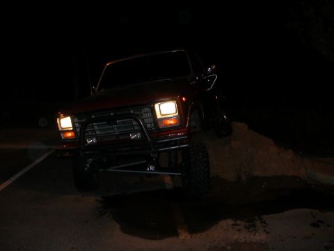 1984 Ford Bronco - This lifted red Ford Bronco is shown at night, partially on a dirt pile.