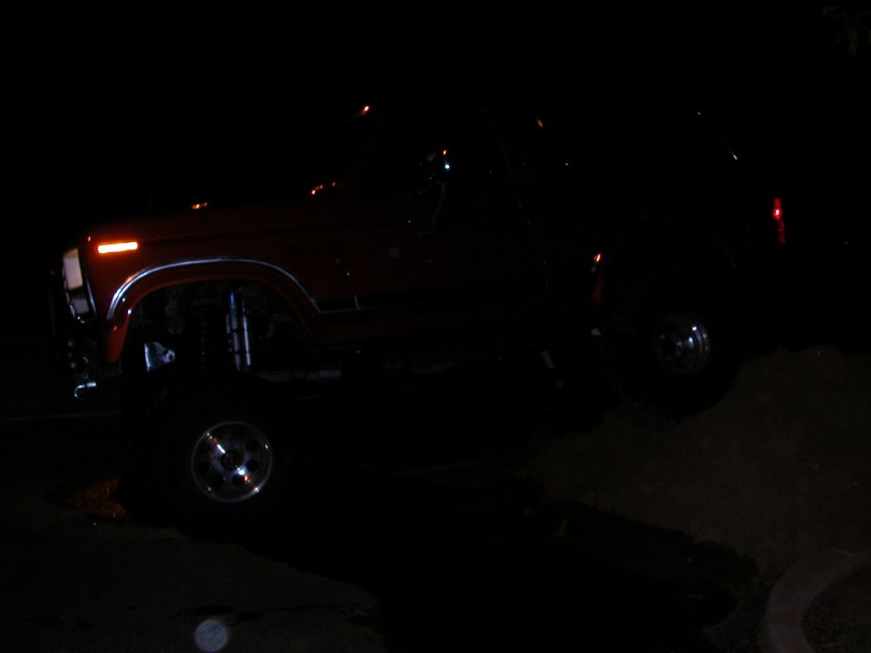 Red SUV with chrome wheels, lifted suspension, and chrome trim on the fender. Visible front turn signal