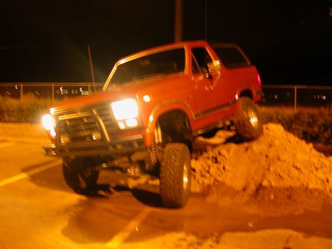 1984 Ford Bronco - This red SUV is shown climbing a dirt pile at night. The vehicle's body style suggests an early 1980s model.