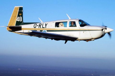 1995 Ford Bronco - A white and green airplane with a dog and pilot inside flies through the sky.