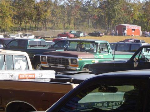 1979 Ford Bronco - A green 1979 Ford pickup truck is visible at an event with a registration building in the background.