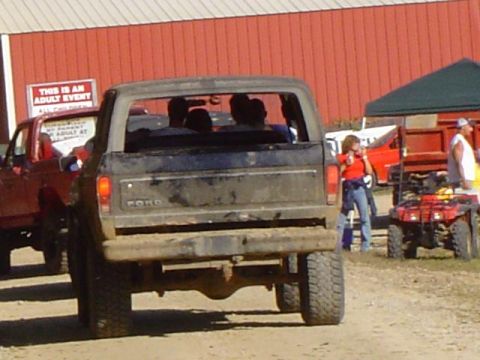 1979 Ford Bronco - A muddy 1979 Ford Bronco is seen from the rear at an outdoor event.