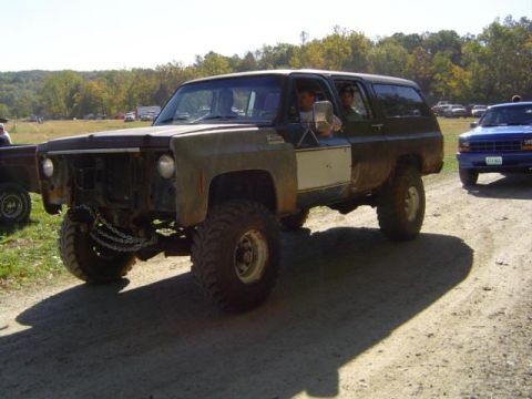 1979 Ford Bronco - An off-road SUV with a modified front end and lifted suspension is seen on a dirt road.