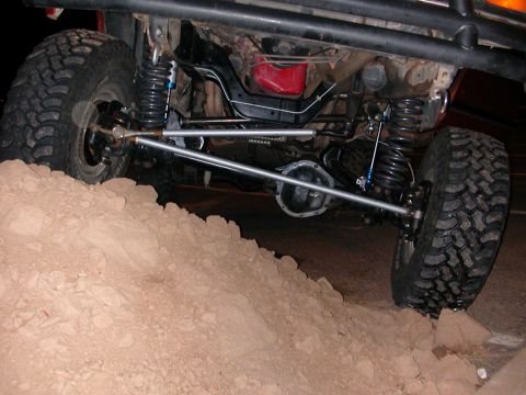 1984 Ford Bronco - Close-up view of the undercarriage and suspension of an off-road vehicle navigating rough terrain.