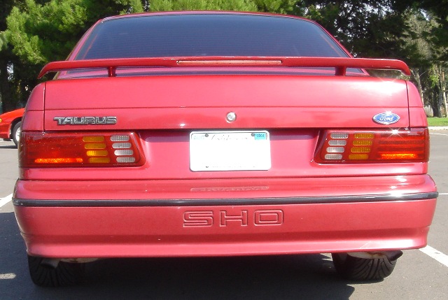 Rear view of red Ford Taurus SHO sedan with trunk spoiler and SHO bumper lettering