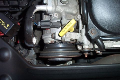 1999 Chrysler 300M - Close-up view of an engine oil dipstick and pulley system within a vehicle's engine compartment.