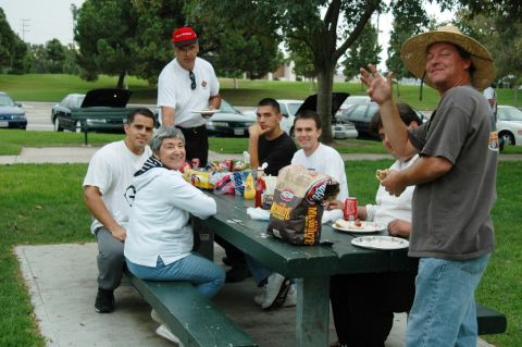 1991 Ford Taurus - A group enjoys a picnic lunch outdoors with several vehicles visible in the background.