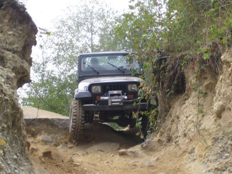 1990 Ford Bronco - A black Jeep Wrangler navigates a challenging rocky off-road trail.