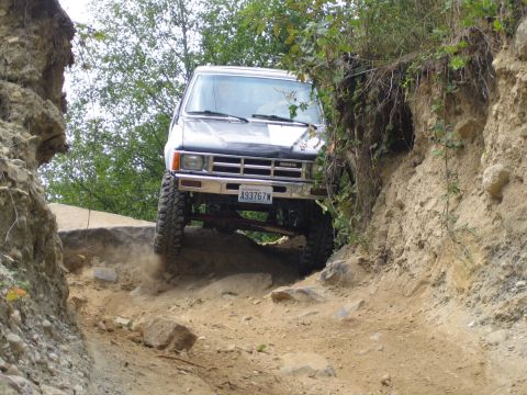 1990 Ford Bronco - Toyota 4Runner tackling a challenging off-road course with steep inclines and rocky terrain.