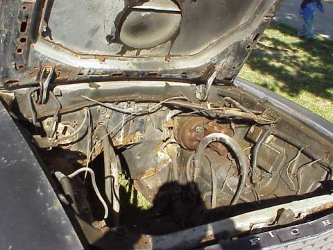 1978 Ford Mustang II - The engine bay of a car shows significant rust and worn components, with a person visible in the background.