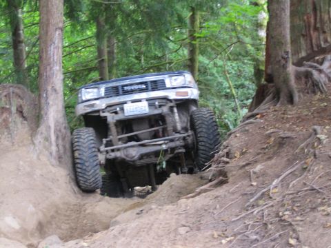 1990 Ford Bronco - This Toyota 4Runner is navigating a challenging off-road trail in a wooded area.
