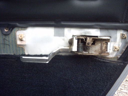close-up of a car's interior door handle mechanism, showing rust and wear