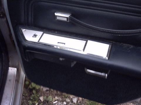 1991 Ford Crown Victoria LTD - Close-up view of a car's interior door panel, showing dark upholstery and chrome trim details.