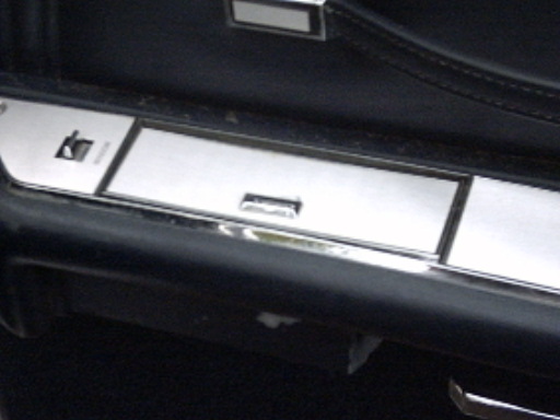 Close-up of a car's interior door panel showing chrome trim, a lock switch, and a pull handle