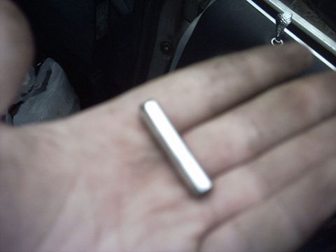 1991 Ford Crown Victoria LTD - A metal rod is held in a hand, with a black bag and interior car details in the background.