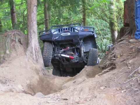 1990 Ford Bronco - Off-road vehicle tackling a challenging trail with significant elevation change.