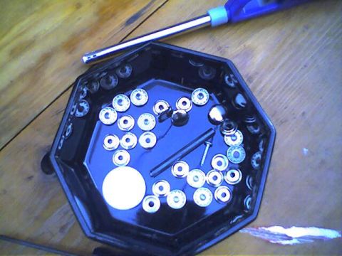1994 Ford Bronco - A collection of small metal parts and a screw are organized in a black tray on a wooden table.