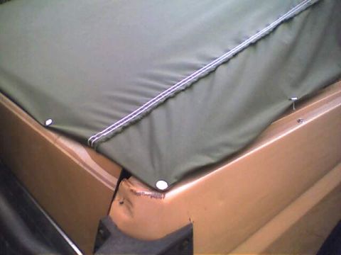 1994 Ford Bronco - Close-up of a green soft top covering the rear section of a tan vehicle.