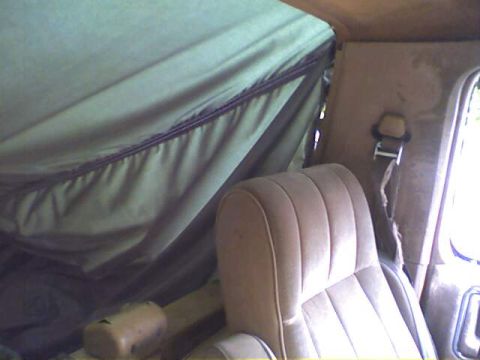 1994 Ford Bronco - The interior of a vehicle shows a tan seat and a green soft top, with a "SUPERMOTORS.NET" watermark visible.