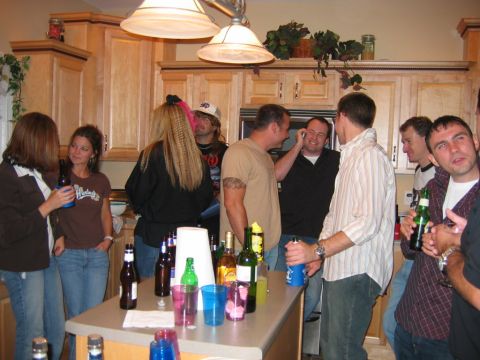 1985 Ford LTD Crown Victoria - A group of friends socialize in a kitchen during a party.