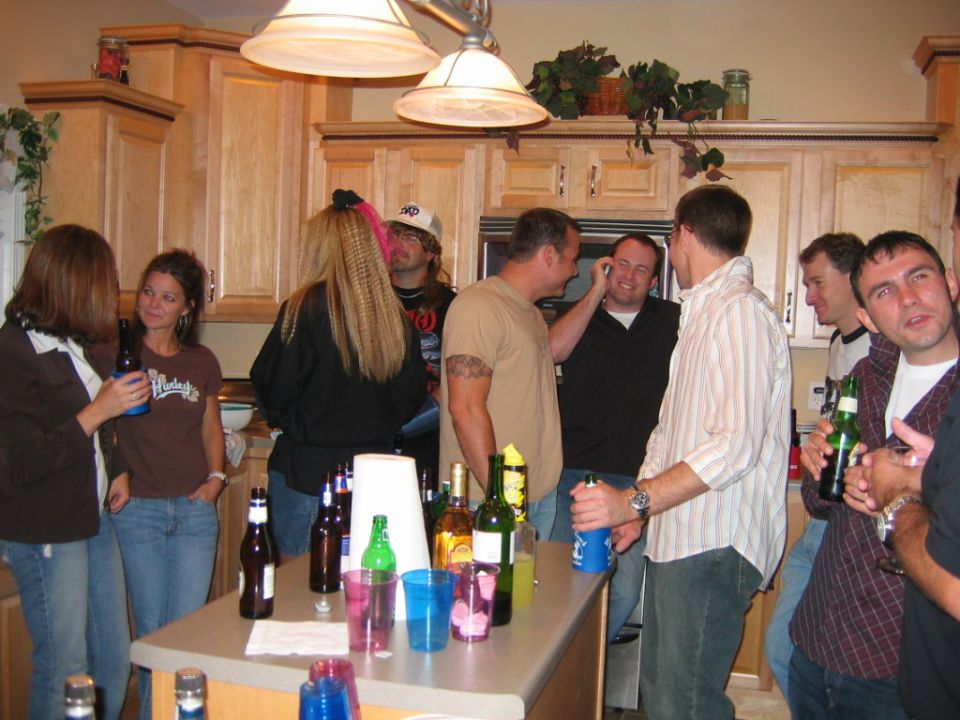People gathered in a kitchen with drinks on the counter