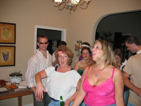 1985 Ford LTD Crown Victoria - A group of friends enjoy a lively party atmosphere, with some dancing and others conversing.