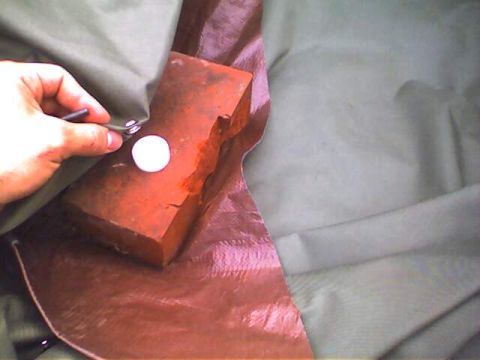1994 Ford Bronco - A hand is shown pressing a snap fastener onto a red brick and fabric material.