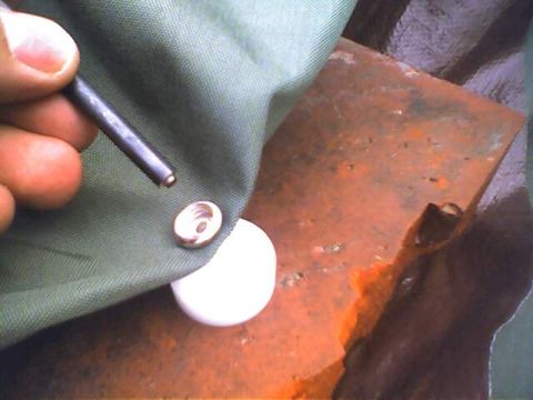 1994 Ford Bronco - Close-up of a hand preparing to attach a snap fastener to green fabric.
