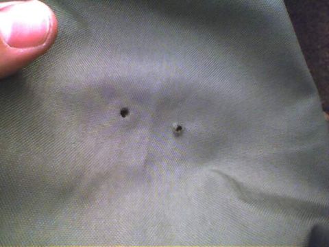 1994 Ford Bronco - A close-up of green fabric shows two small holes, possibly from wear or damage.