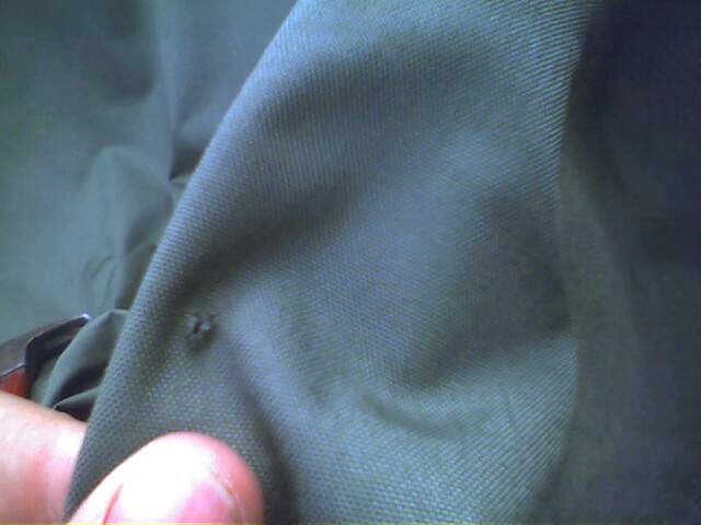 Close-up of green fabric showing a small tear