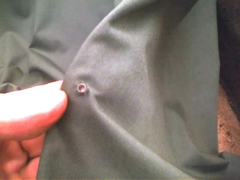 1994 Ford Bronco - A close-up shows a grommet on a piece of green fabric, possibly a soft top.