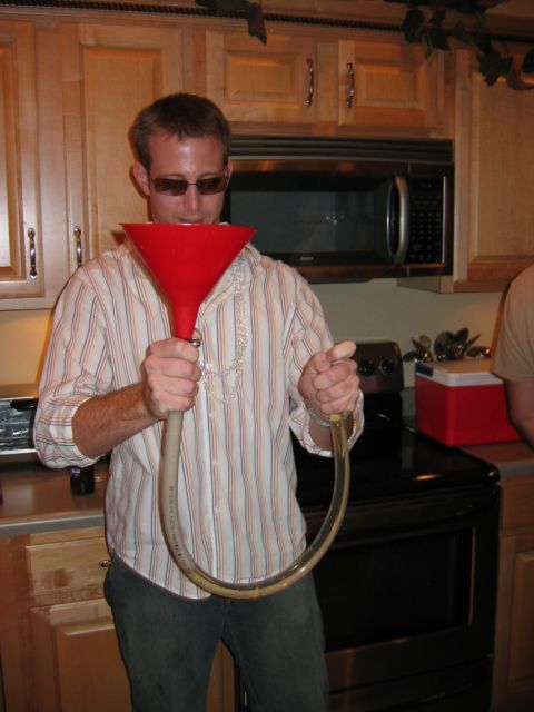 1985 Ford LTD Crown Victoria - A man uses a beer funnel in a kitchen setting.
