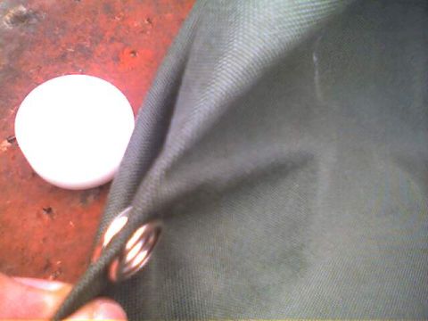 1994 Ford Bronco - A close-up view of a green fabric part with grommets, possibly for a vehicle cover or top.