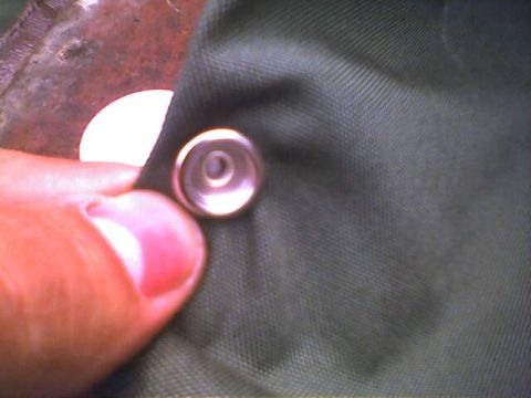 1994 Ford Bronco - A snap fastener is shown on green fabric, with a thumb and fingernail in the frame.