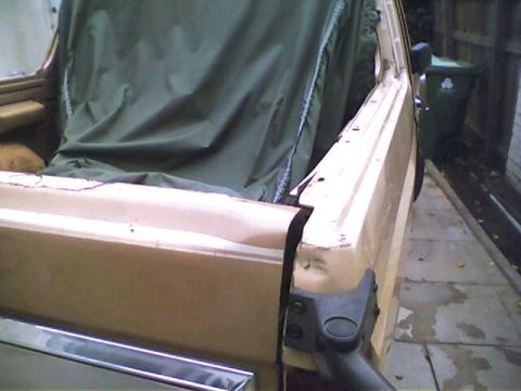 1994 Ford Bronco - The 1994 Ford Bronco's side profile is visible, with the soft top removed, revealing the interior and a green tarp.