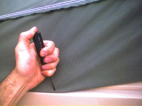 1994 Ford Bronco - A hand holds a T-15 hex wrench, with a dark green fabric and a hint of a light-colored surface visible.