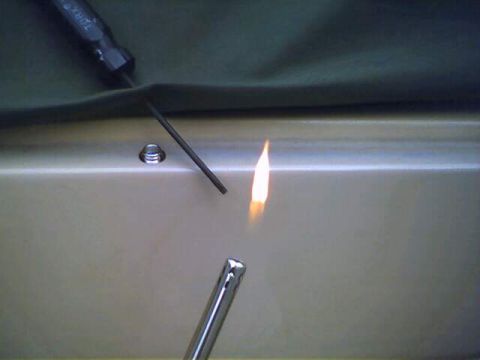 1994 Ford Bronco - A soft top is being worked on with a torch, with a screw visible nearby.