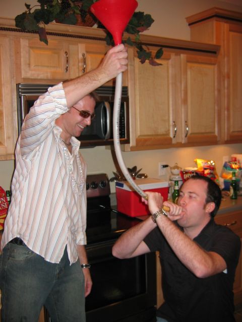 1985 Ford LTD Crown Victoria - Two friends are enjoying a party with a beer funnel in a kitchen setting.