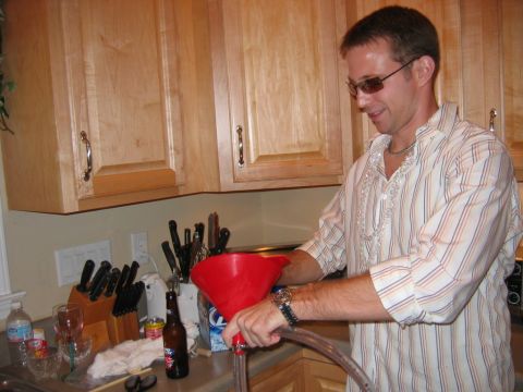 1985 Ford LTD Crown Victoria - A man is seen in a kitchen pouring liquid through a red funnel into a tube.