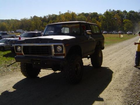 1979 Ford Bronco - Modified Ford Bronco with large tires on a dirt road during an outdoor event.