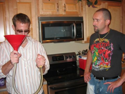 1985 Ford LTD Crown Victoria - Two men are in a kitchen, one holding a funnel and hose, the other wearing a monster t-shirt.