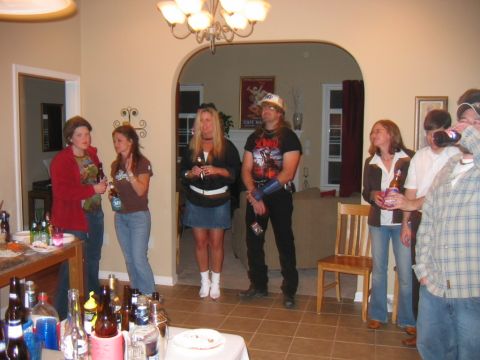 1985 Ford LTD Crown Victoria - Several people are standing around in a room, holding drinks and socializing at a party.