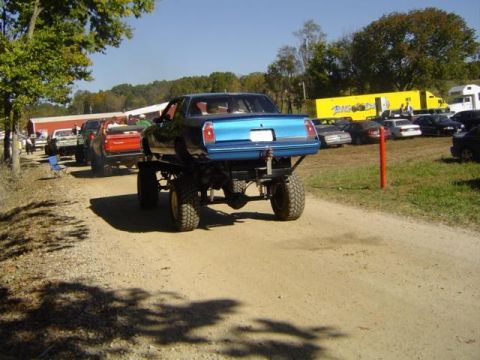 1979 Ford Bronco - A modified vehicle with a car body atop a monster truck frame is seen at an outdoor event.