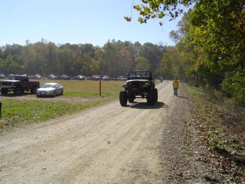 1979 Ford Bronco - A group of vehicles are gathered in a field on a sunny day with trees in the background.